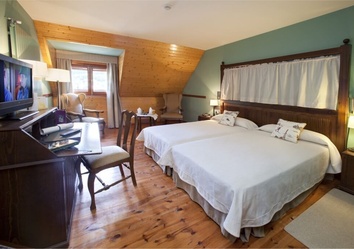 Gästezimmer im Parador de Arties mit Holzmöbeln und Aussicht auf Berge und Wälder