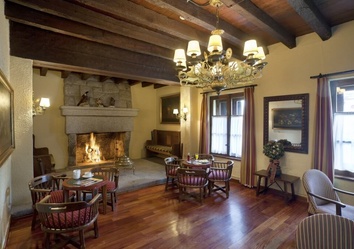 Gemütliche Lobby im Parador de Arties mit Kaminfeuer, Holzdecke und Sesseln