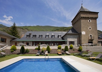 Garten des Parador de Arties mit Liegewiese, Bäumen und Blick auf die Berge des Val d’Aran