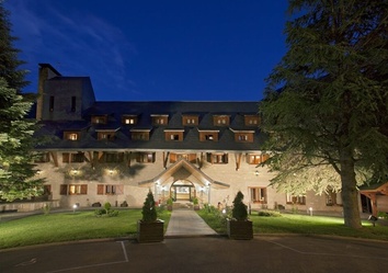 Parador de Arties in der Abenddämmerung, beleuchtete Fassade vor Bergkulisse